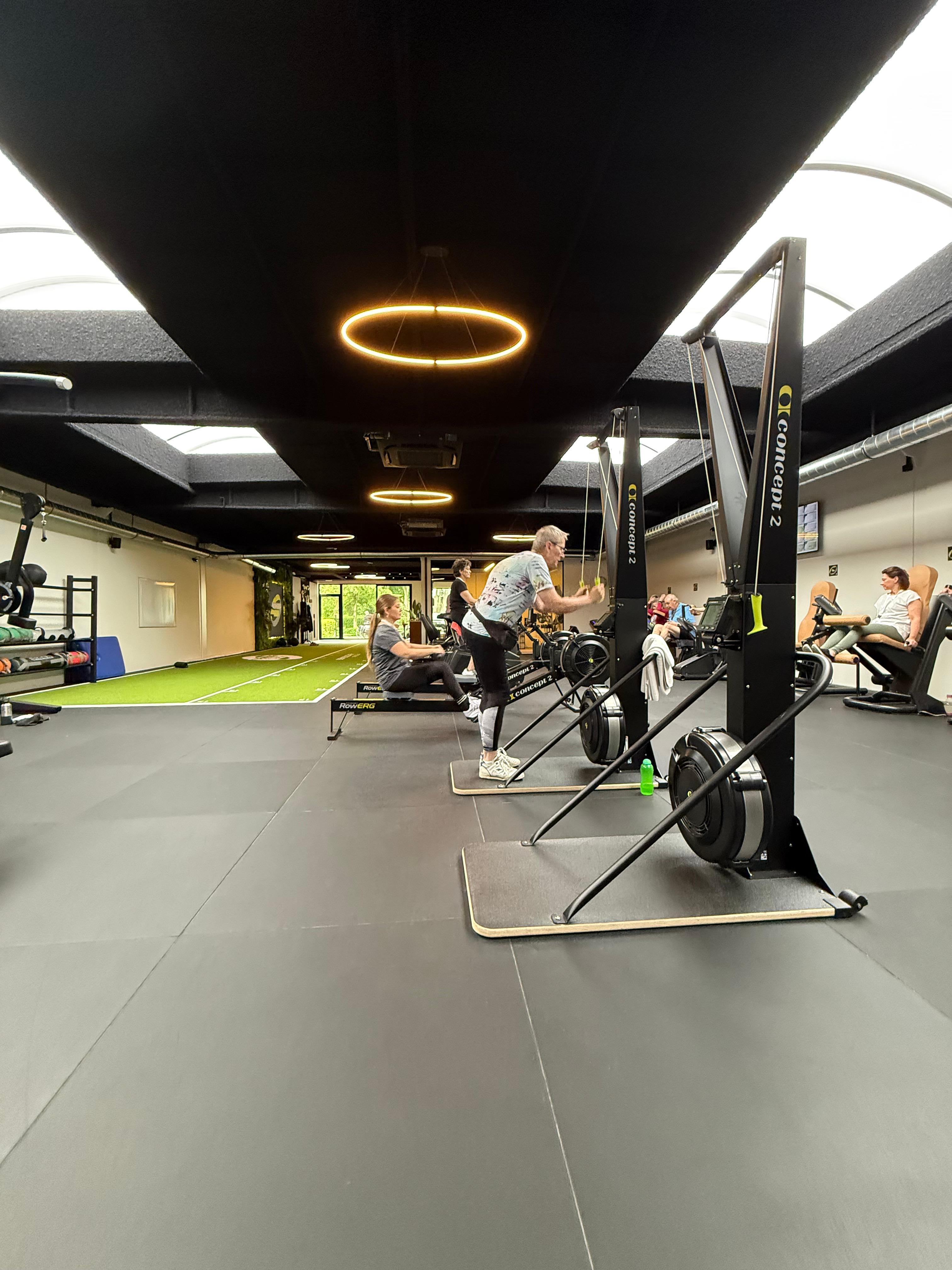 Beweegcoach Brasschaat met Acospray® DC3 in Basic Black aangebracht door Acosorb. Het donkere akoestisch spuitwerk absorbeert galm in de open trainingsruimte en versterkt de premium boutique gym-uitstraling.